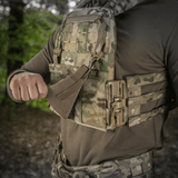 M‑Tac Front Panel til Cuirass QRS i brug med militær MOLLE-system, ideel til fastgørelse på taktisk udstyr i skovmiljø.