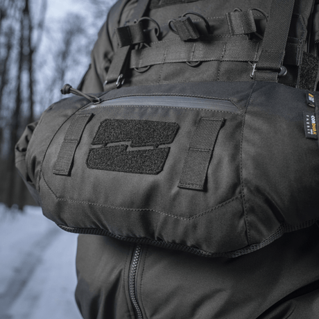 Person iført M-Tac Taktisk Håndvarmer Elite i snefyldt skovmiljø, fremstillet af slidstærkt Cordura 500D med blødt Polartec® fleecefor.