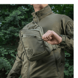 Person iført M-Tac Sling Pistoltaske Elite Hex udendørs i komfortabel og holdbar taske med justerbar rem og rummelige rum.