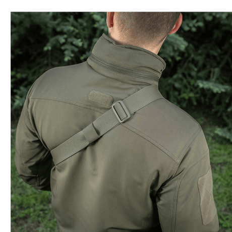 Mand bærer M-Tac Sling Pistoltaske Elite Hex med justerbar skulderrem i en udendørs setting