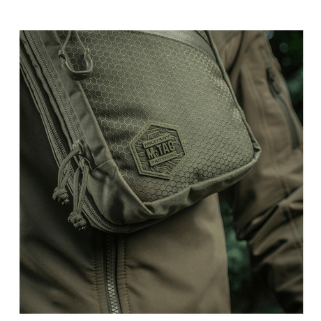 M-Tac Sling Pistoltaske Elite Hex på en person iført jakke, fremstillet i slidstærkt Cordura 1000D materiale med justerbar rem.