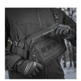 Person i sort jakke demonstrerer M-Tac Admin Taske Elite lavet af slidbestandigt Cordura materiale med lynlås og spænder i høj kvalitet.