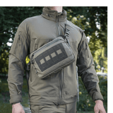 M-Tac Admin Taske Elite bæres af en person i skovmiljø, lavet af slidstærkt Cordura 500D og Hex med kvalitetslynlåse.