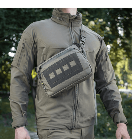 M-Tac Admin Taske Elite bæres af en person i skovmiljø, lavet af slidstærkt Cordura 500D og Hex med kvalitetslynlåse.