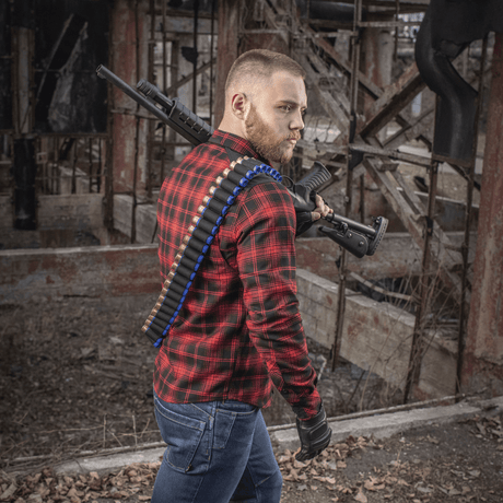 Mand iført M-Tac Bandolier Elite med patroner, klar til jagt eller skydesport, stående i et industrielt miljø.