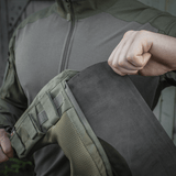 Person demonstrerer montering af M-Tac Skulderpude til Plate Carrier Cuirass QRS på jakke med Velcro fastgørelsessystem.