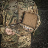Mand holder M-Tac Utility Organizer Slim Elite med gennemsigtig forvæg og robust Cordura 500D-materiale udendørs i camouflagejakke.