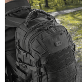 Mand iført M-Tac Mission Pack Elite rygsæk med ergonomisk design og MOLLE LASER CUT-system i skovmiljø