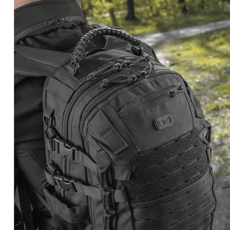 Mand iført M-Tac Mission Pack Elite rygsæk med ergonomisk design og MOLLE LASER CUT-system i skovmiljø