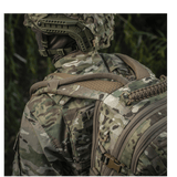 Person iført camouflageuniform og M-Tac Mission Pack Elite med MOLLE LASER CUT i skovmiljø for ergonomisk funktionalitet.