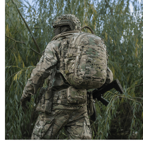 Soldat med M-Tac Mission Pack Elite rygsæk i camouflage, i naturmiljø.