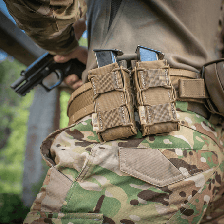 Person med taktisk udstyr, bærer M-Tac Pistolmagasinlomme Kolchan på bæltet, fremstillet af hårdfør Cordura 1000D, til sikker magasinhåndtering.