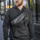 Mand bærer M‑Tac Bæltetaske Elite Hex i bymiljø, fashionabel og funktionel med Cordura og YKK lynlåse, perfekt til hverdagsbrug.