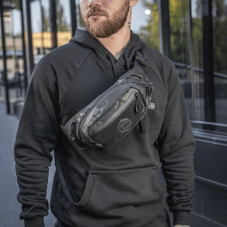Mand bærer M‑Tac Bæltetaske Elite Hex i bymiljø, fashionabel og funktionel med Cordura og YKK lynlåse, perfekt til hverdagsbrug.