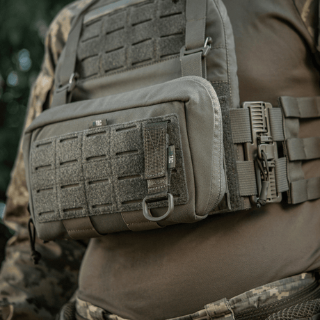 M-Tac Fastgørelse med D-ring monteret på taktikvest med MOLLE-system for sikker ophængning af udstyr via Velcro-lukning.