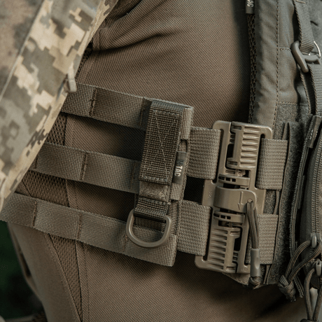 M-Tac Fastgørelse med D-ring fastgjort på MOLLE-udstyr med Velcro, ideel til taktisk brug med sikker ophængning og justerbar pasform.