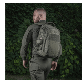 Person med en M-Tac Mission Rygsæk Elite Hex baggrund af grøn bevoksning.