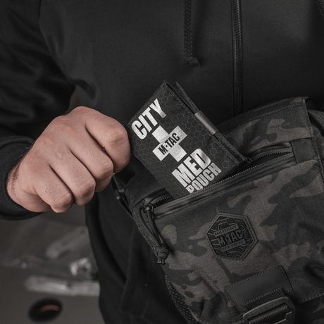 M-Tac City Med Pouch Hex, kompakt førstehjælpskit i Hex Polyester, holdes af person og vises ved taske, med synligt M-Tac-logo.