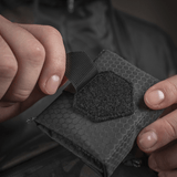 Person åbner M-Tac City Med Pouch Hex fremstillet af slidstærkt Hex Polyester med velcrolukning.