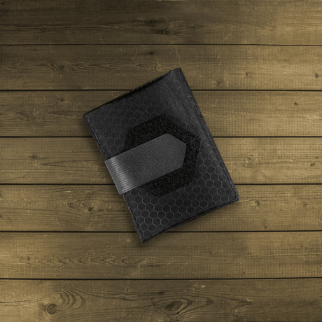 M-Tac City Med Pouch Hex, bærbart førstehjælpskit i slidstærkt Hex Polyester med Velcro-lukning, set på træbaggrund.