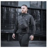 Mand bærer M-Tac Cross Taske Slim Elite Hex, en stilfuld og funktionel taske lavet af Cordura med YKK og Woojin tilbehør.