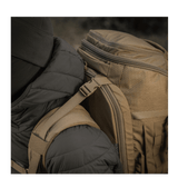 Person med M-Tac Rygsæk Large Elite Hex Gen. IV, ergonomisk og funktionel, designet til at bære våben, lavet af slidstærk Cordura.