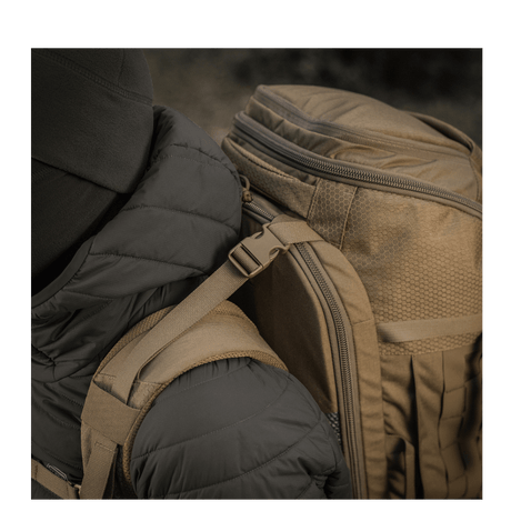 Person med M-Tac Rygsæk Large Elite Hex Gen. IV, ergonomisk og funktionel, designet til at bære våben, lavet af slidstærk Cordura.