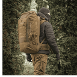 En person iført M-Tac Rygsæk Large Elite Hex Gen. IV i naturen, designet til holdbarhed og funktionalitet.