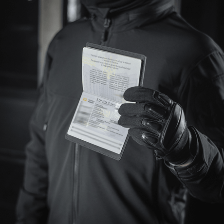 Person med M‑Tac Pascover holder et pas, beskytter mod slid og skader, moderne polymer, stilfuldt design, ideel til rejser.