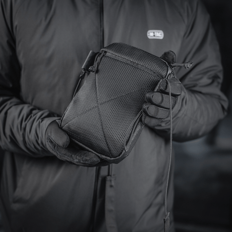 M‑Tac Pocket Bag Elite HEX i sort, holdt af en person med handsker. Kompakt taske perfekt til opbevaring af diverse småting.