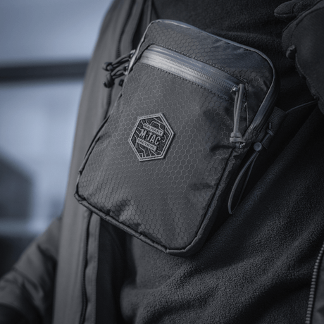En person bærer en kompakt, robust M‑Tac Pocket Bag Elite HEX med slidstærke YKK lynlåse, ideel til hverdagens opbevaringsbehov.