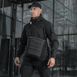 Mand med M-Tac Tablet Bag Laser Cut Hex i sort, ideel til EDC, dokumenter og tablet, fremstillet i holdbart Cordura-materiale.