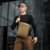 Mand bærer M-Tac Tablet Bag Laser Cut Hex foran kontorbygning, diskret skuldertaske til EDC og dokumenter.