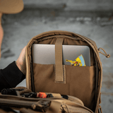 Person kigger i M-Tac Tablet Bag Laser Cut Hex med tablet i indvendig lomme, perfekt til EDC og skjult opbevaring.