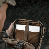 Person åbner M-Tac Tablet Bag Laser Cut Hex med indhold som tablet og dokumenter