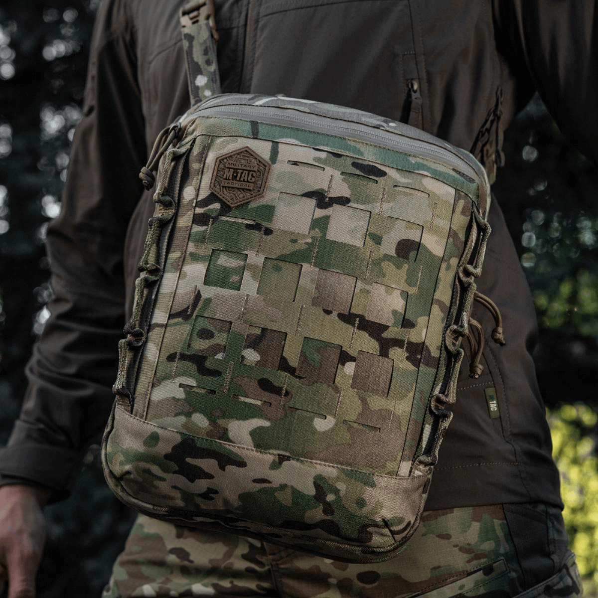 M-Tac Tablet Bag Laser Cut Hex i camouflagedesign med Laser Cut MOLLE og holdbart Cordura-materiale, bæres af en person i naturen.