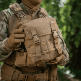 M-Tac Sukharka Gen.3 Pouch i brug i marken, robust feltpose med Cordura 500D og MOLLE-interface til taktisk udstyr, viser detaljerne.