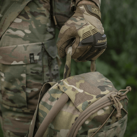 M-Tac STURM Elite Rygsæk i camouflage mønster med MOLLE system, holdt af person i army tøj og taktiske handsker, 15 liter kapacitet.