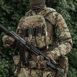 Soldat i fuldt udstyr med M-Tac Frontpanel til Cuirass QRS Pladebærer Tre Magasiner og riffel i skovområde