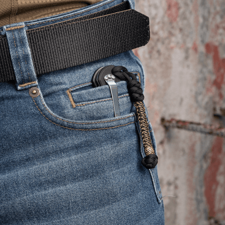 M-Tac Knife Lanyard Scandinavian i flettet paracord på en lommekniv i buksens lomme, stilfuldt og praktisk tilbehør.