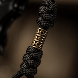 Detaljeret billede af M-Tac Zeus Lanyard med flettet paracord og dekorativt messingstykke, perfekt til kniv og udstyr.