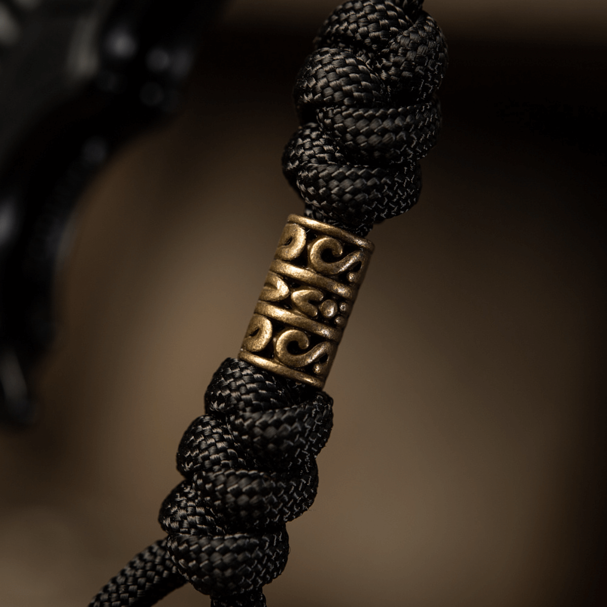 Detaljeret billede af M-Tac Zeus Lanyard med flettet paracord og dekorativt messingstykke, perfekt til kniv og udstyr.