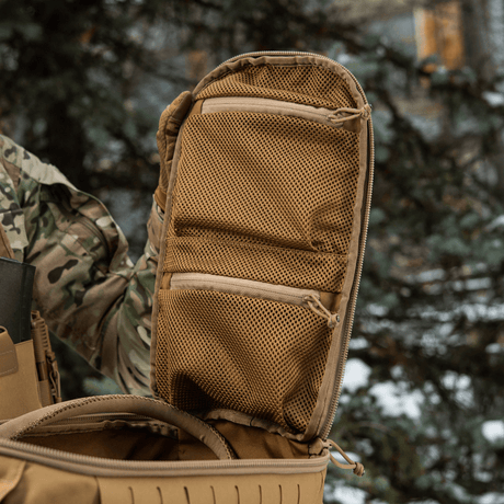 M-Tac Rygsæk Sturm Elite Gen.II med åbnet kuffertstil rum og to netlommer til EDC-udstyr udenfor i et skovmiljø.