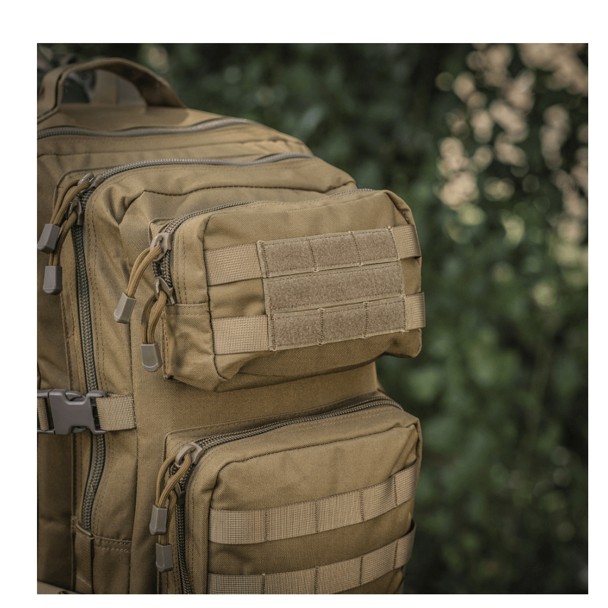 M-Tac Large Assault Pack Rygsæk i taktisk design med MOLLE-system og ekstra lommer, set i tæt skovområde.
