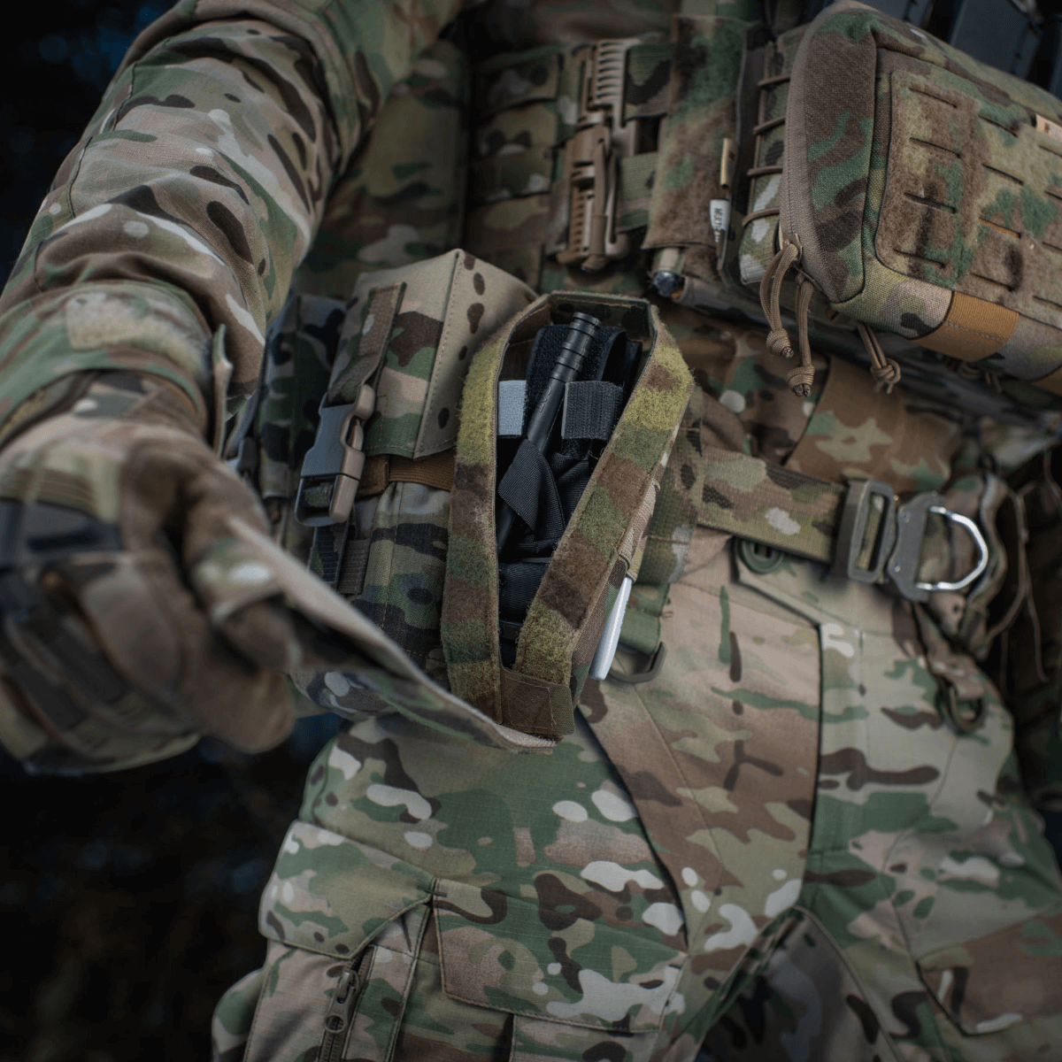 M-Tac Lomme til Tourniquet Closed fastgjort til militæruniform i felten, sikrer hurtig adgang til førstehjælpunder nødsituationer.