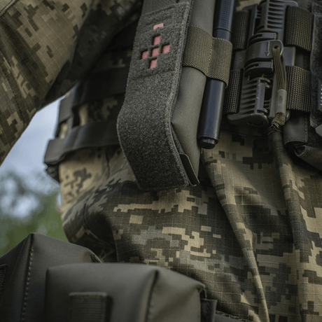 M-Tac Lomme til Tourniquet Closed fastgjort til militæruniform, designet til at beskytte og sikre tourniquet i nødsituationer.