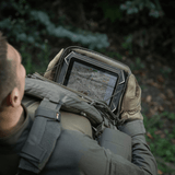 Person med M-Tac Admin Pouch Large Elite holder en tablet i en skov.