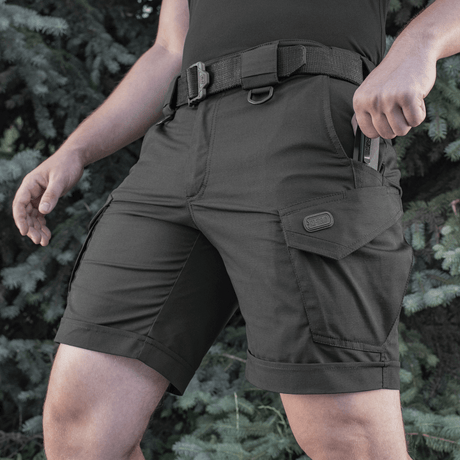 Mand iført M-Tac Shorts Aggressor Short, ideel til varme dage og aktive byaktiviteter, med taktiske funktioner og rip-stop materiale.