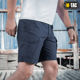 Mand iført M-Tac Shorts Aggressor Short i blå, ideel til taktisk brug på varme dage, fremstillet af elastisk polycotton rip-stop.