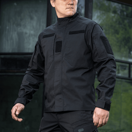 Mand iført sort M-Tac Jakke Patrol Flex med velcro-paneler, skjulte brystlommer og ventilationsøjer for taktisk brug